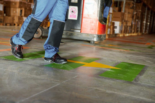 Warehouse worker crossing marked pedestrian walkway near forklift traffic zone